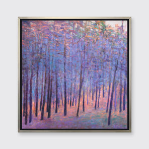 A blue and pink abstract tree landscape print in a silver floater frame hangs on a white wall.