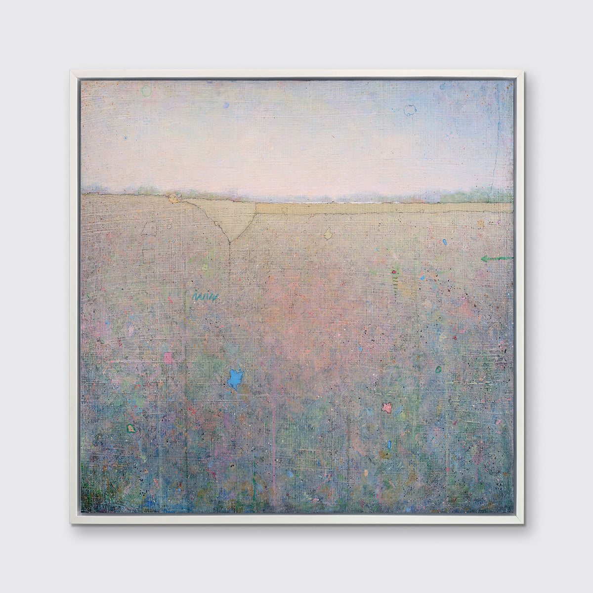 A green, pink and blue abstract landscape print in a silver floater frame hangs on a white wall.