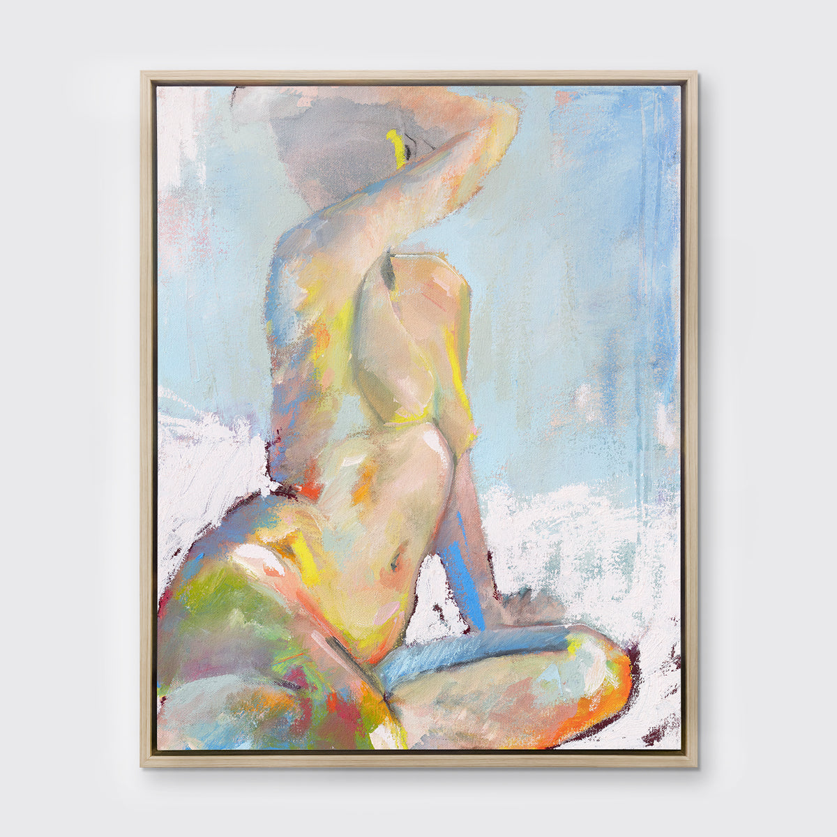A multicolored abstract figural print in a white oak wood floater frame hangs on a white wall.
