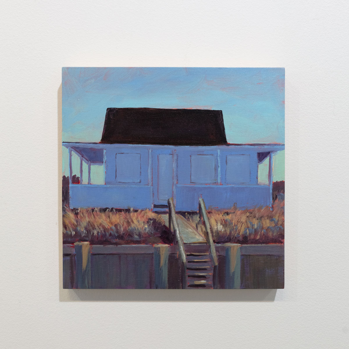 A small painting of a blue house with steps is hung on a gallery wall.