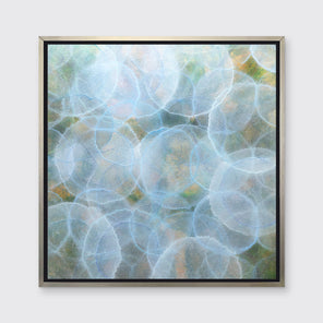 A light blue, green and yellow abstract geometric print in a silver floater frame hangs on a white wall.