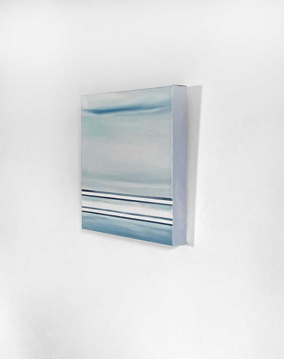 A right side-angle view of a blue and white linear abstract painting hanging on a white wall.