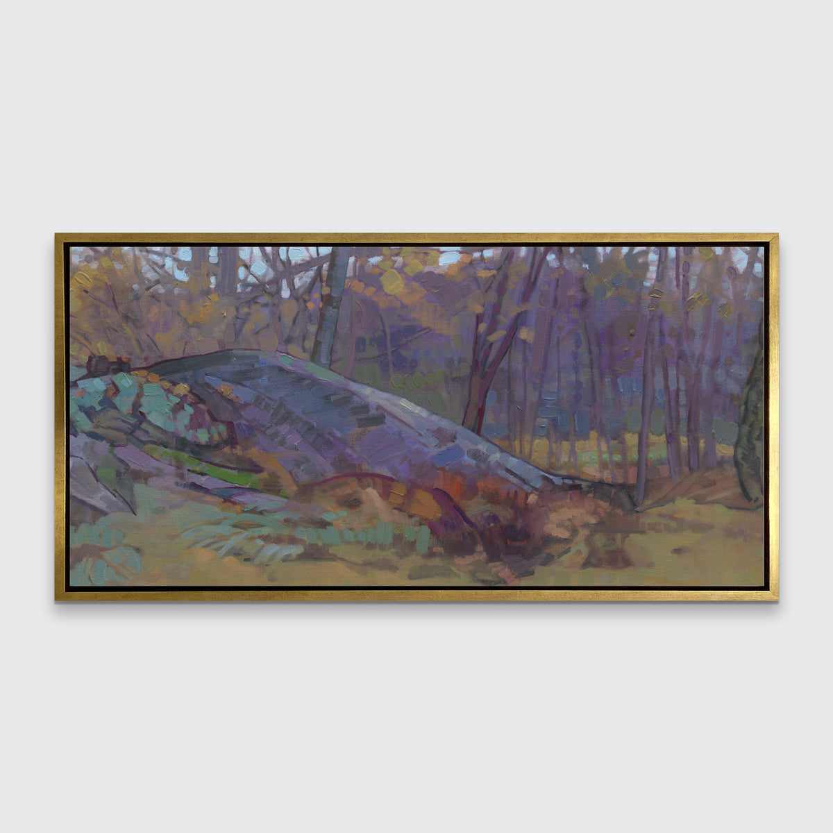 A muted multicolored abstract landscape print in a gold floater frame hangs on a white wall.