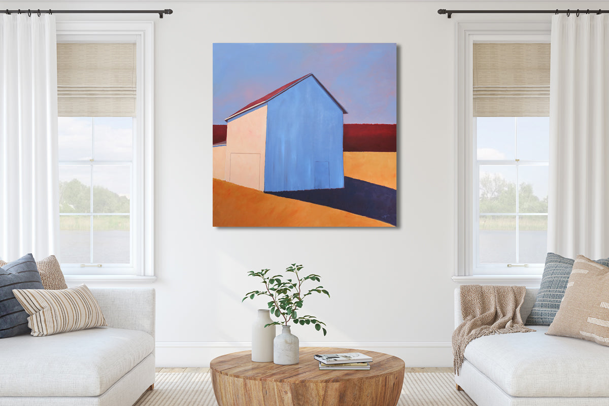A painting of a white barn casting a long shadow is hung in a white living room.