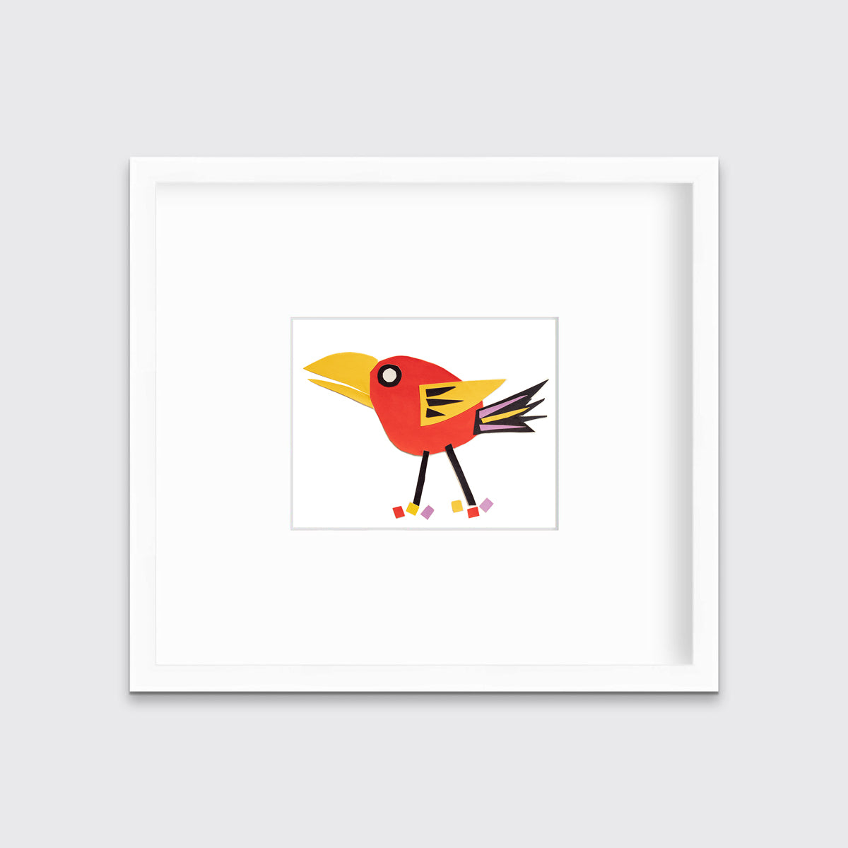A red bird collage in a white frame with a mat hangs on a white wall.