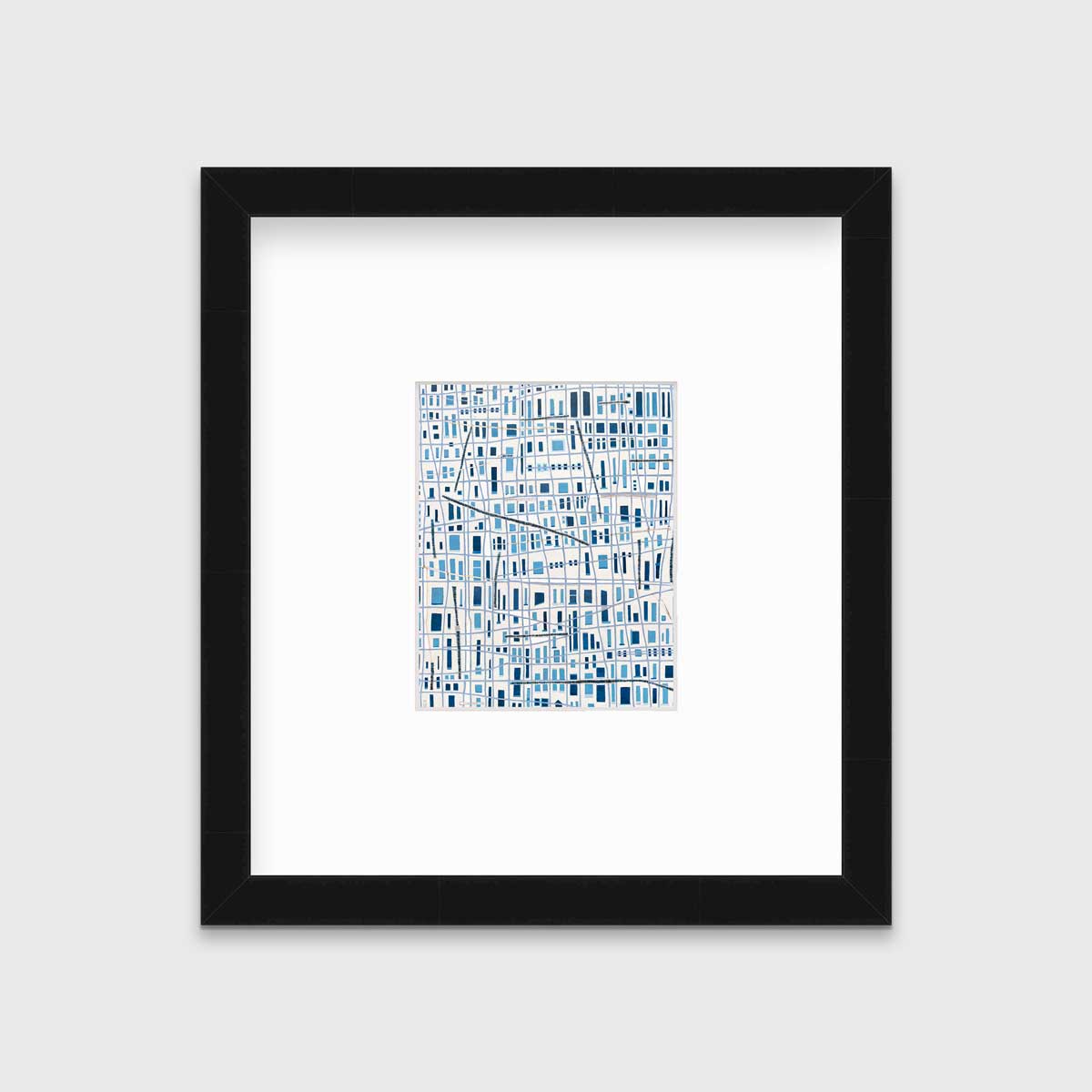 A blue and white geometric abstract print in a black frame with a mat hangs on a white wall.