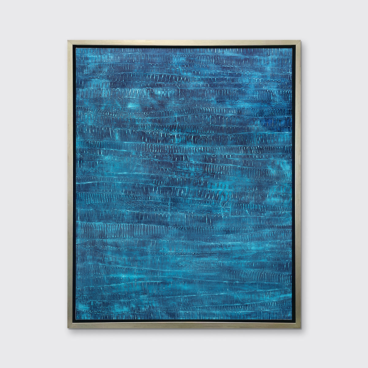 A dark teal abstract print in a silver floater frame hangs on a white wall.