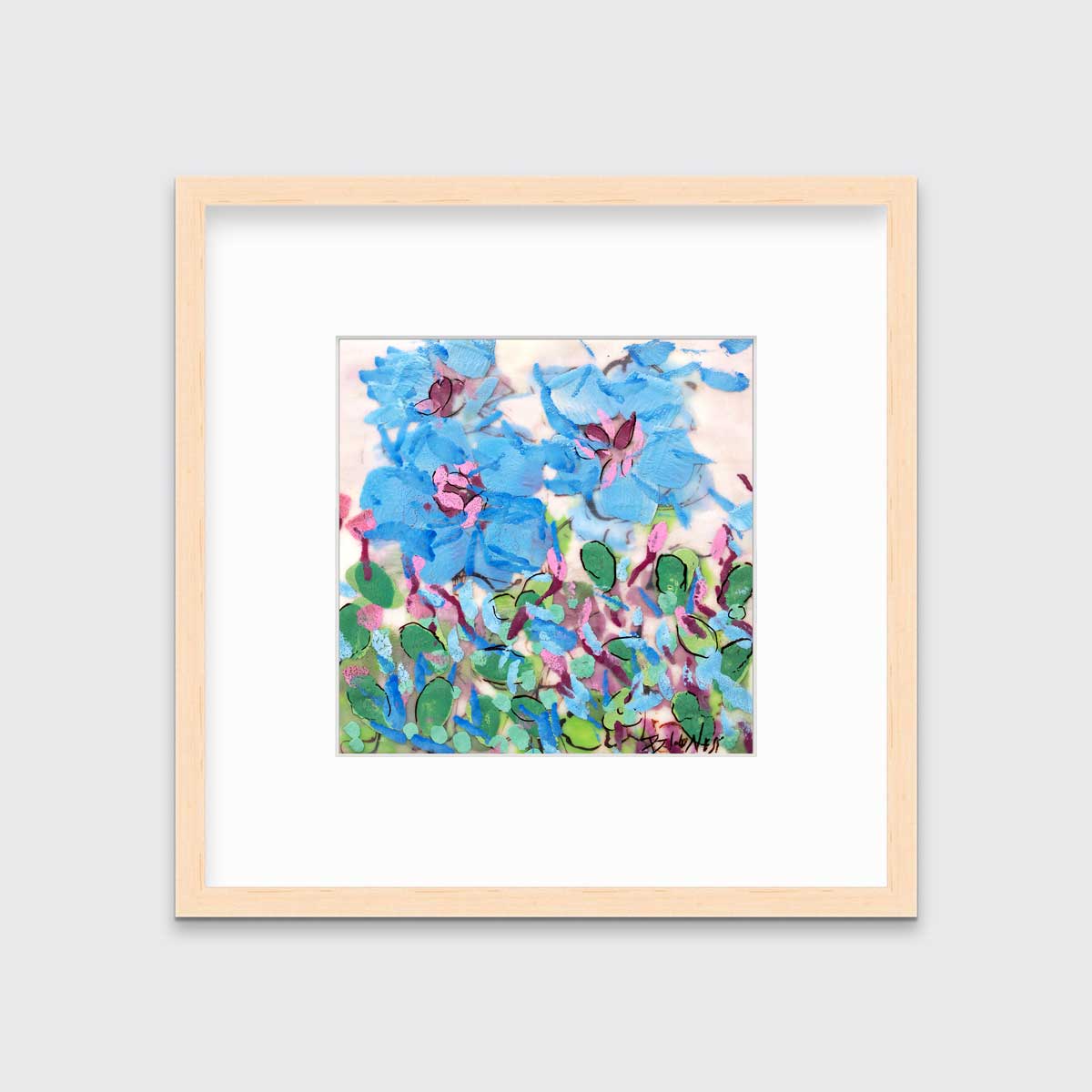 A blue, pink, green and white abstract floral print in a natural wood frame with a mat hangs on a white wall.