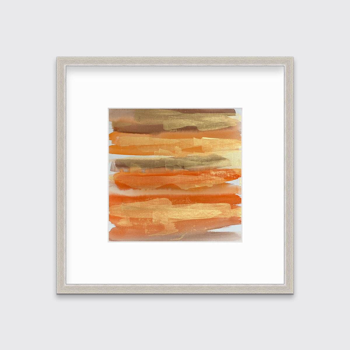 A gold, orange and light brown abstract print in a silver frame with a mat hangs on a white wall.