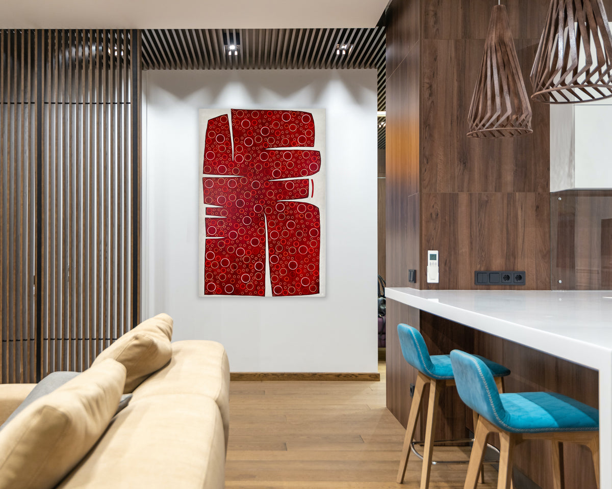 A large abstract painting of an irregular red form containing yellow and white circles is hung in a kitchen area.