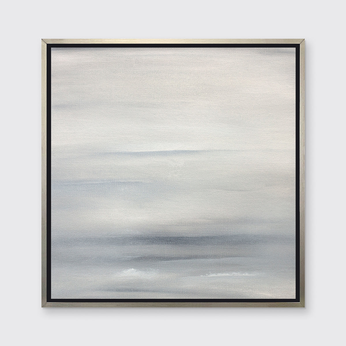 A tonal grey print in a silver floater frame hangs on a white wall.