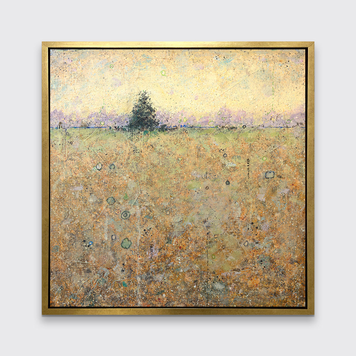 A yellow and green abstract landscape print with a tree in a gold floater frame hangs on a white wall.