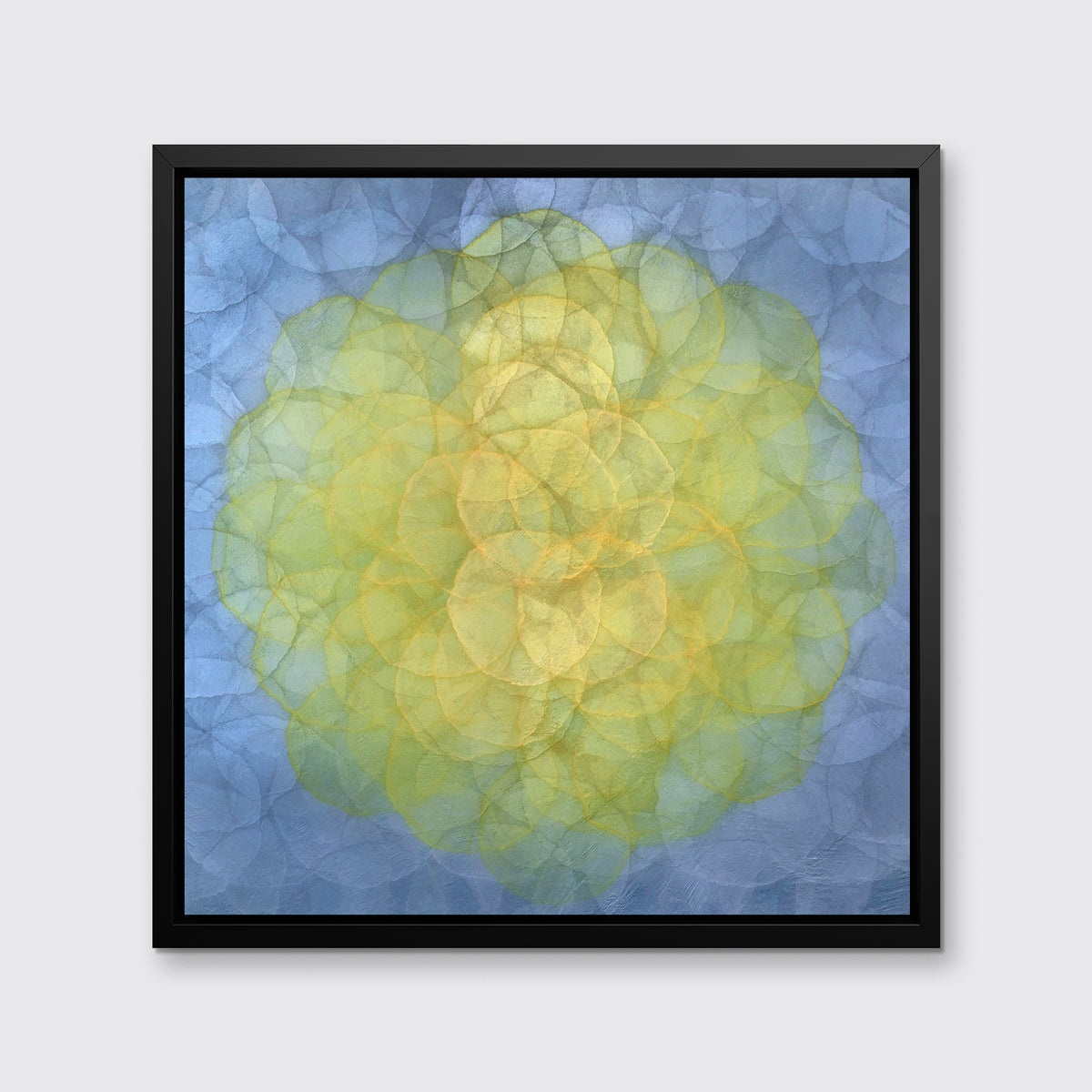A blue and yellow abstract geometric print in a black floater frame hangs on a white wall.
