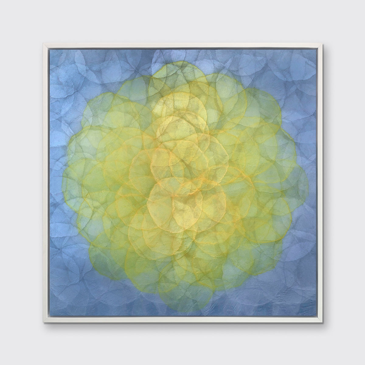 A blue and yellow abstract geometric print in a white floater frame hangs on a white wall.