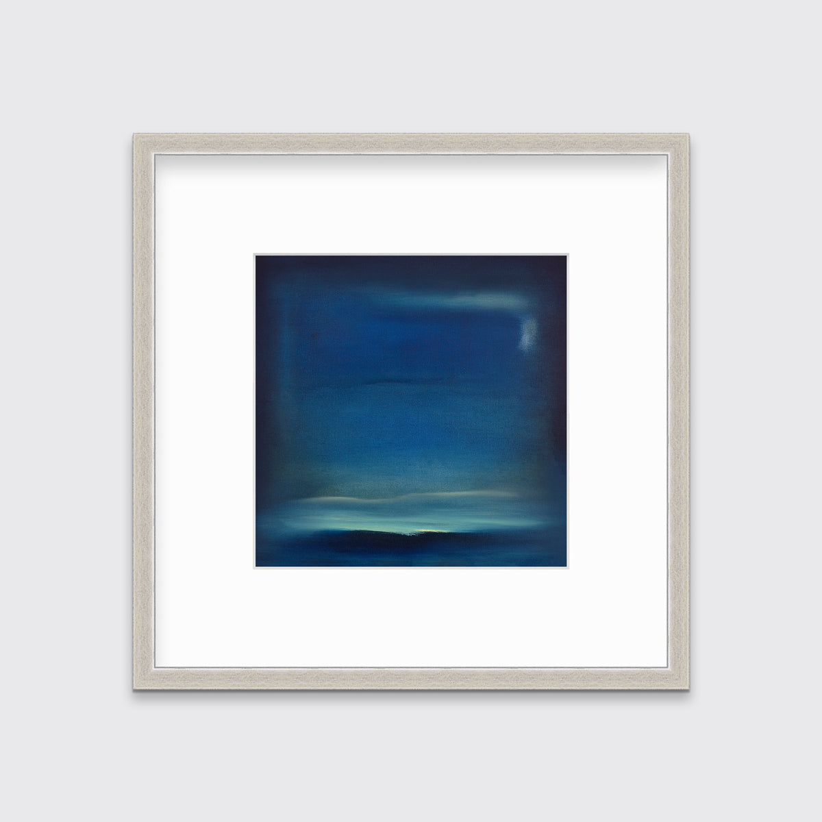 A dark blue and teal with accents of light yellow abstract print in a silver frame with a mat hangs on a white wall.