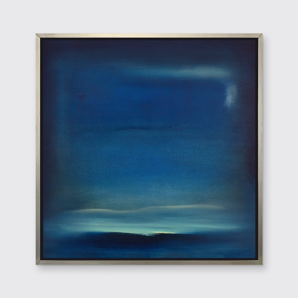 A dark blue and teal with accents of light yellow abstract print in a silver floater frame hangs on a white wall.