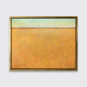 A yellow and orange abstract landscape print in a gold floater frame hangs on a white wall.