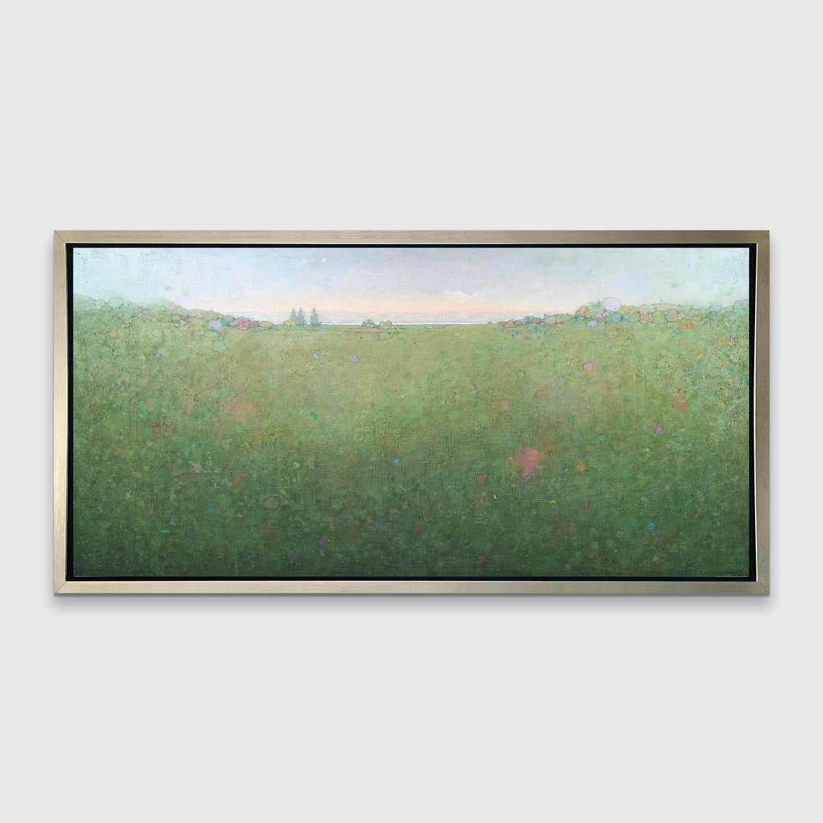 A green abstract landscape print in a silver floater frame hangs on a white wall.