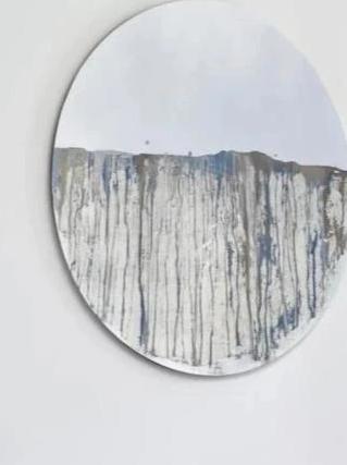 Circular mirror, mounted on wall, with blue and gold mixed media painting on lower half.