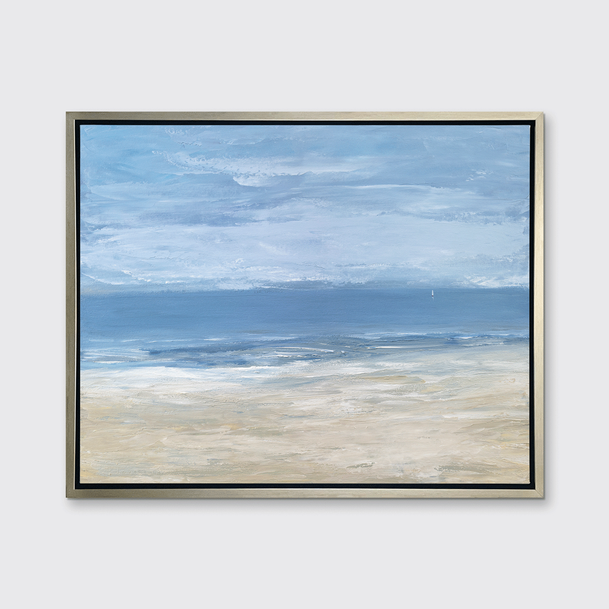 A blue, light blue, white and beige abstract seascape print in a silver floater frame hangs on a white wall.