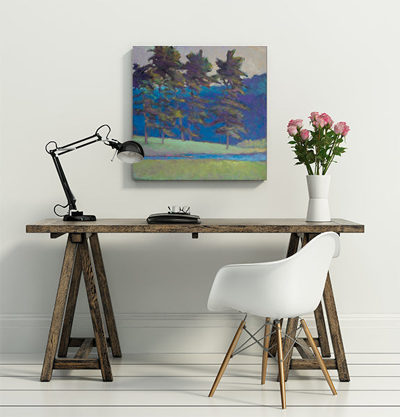 The painting, At the Creek's Edge by Ken Elliott hanging on a white wall above a wooden desk and white chair.