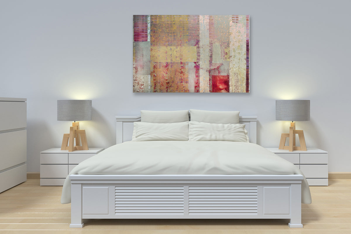 A red, yellow and grey abstract print hangs on a white wall above a white bed with four pillows and two white side tables with matching lamps.