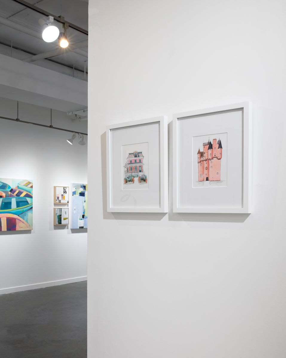 Two architectural illustration drawings in white frames with mats hang on a white wall.