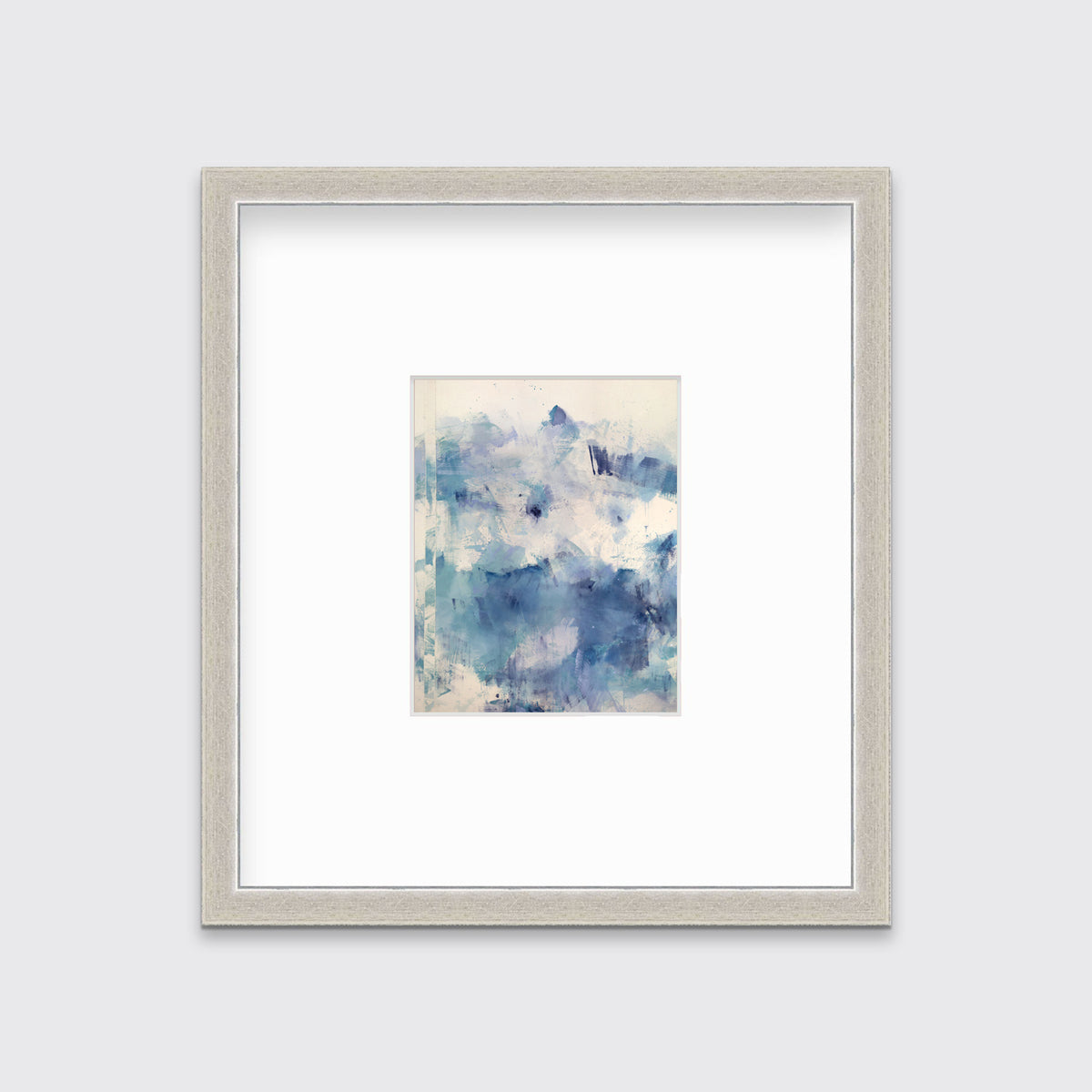 A blue abstract print matted and framed in a silver frame hangs on a white wall.