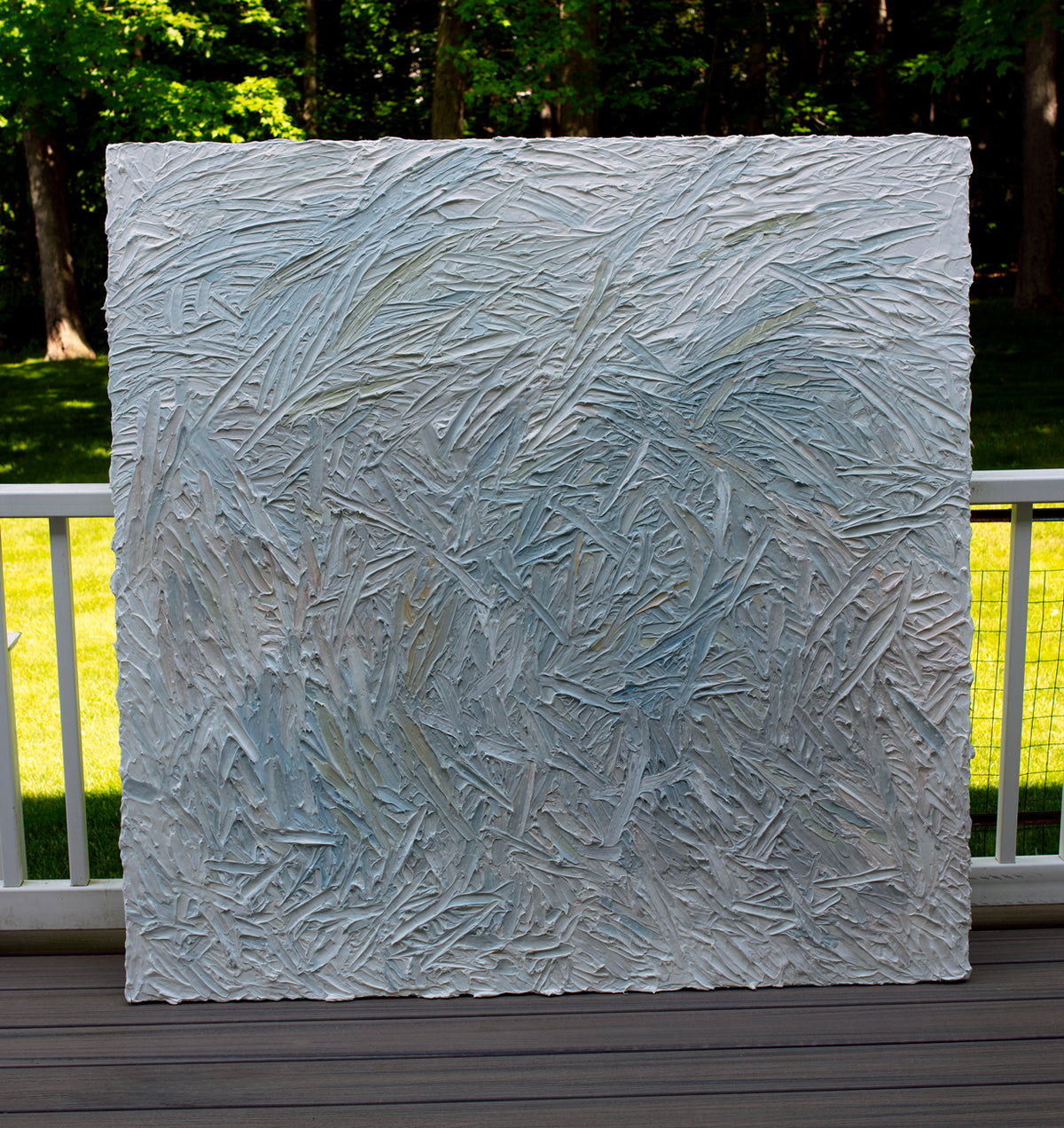 Original abstract painting with thick texture by artist Teodora 'Teo' Guererra on a wooden deck with greenery in the background
