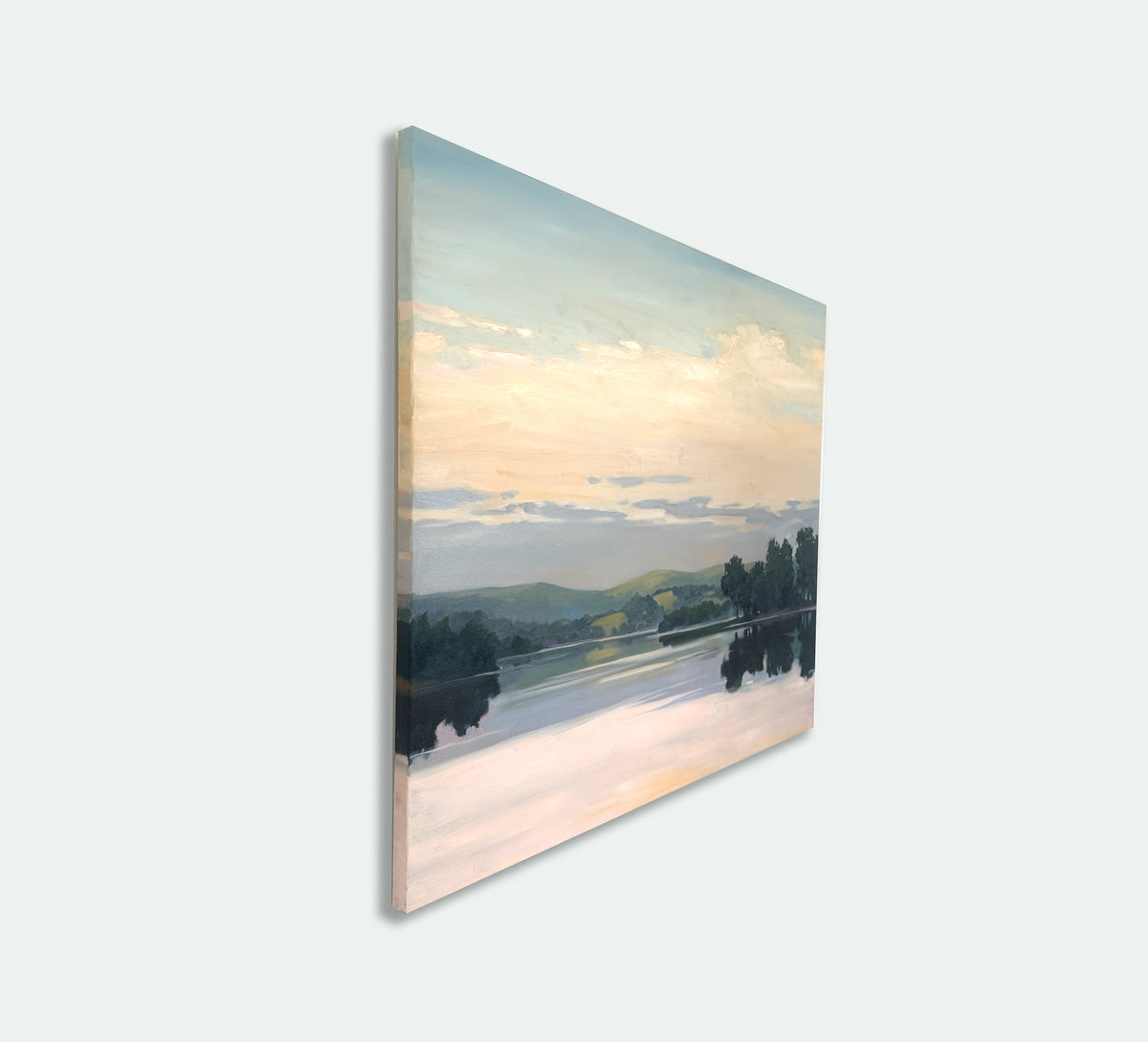 An original landscape painting, side view, with trees and a river under a colorful sky hanging on a white wall.