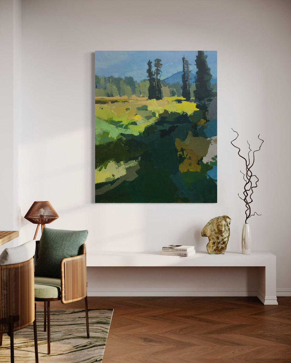 An abstracted blue and yellow painting hangs on a white wall over a white bench with decorative adornments.