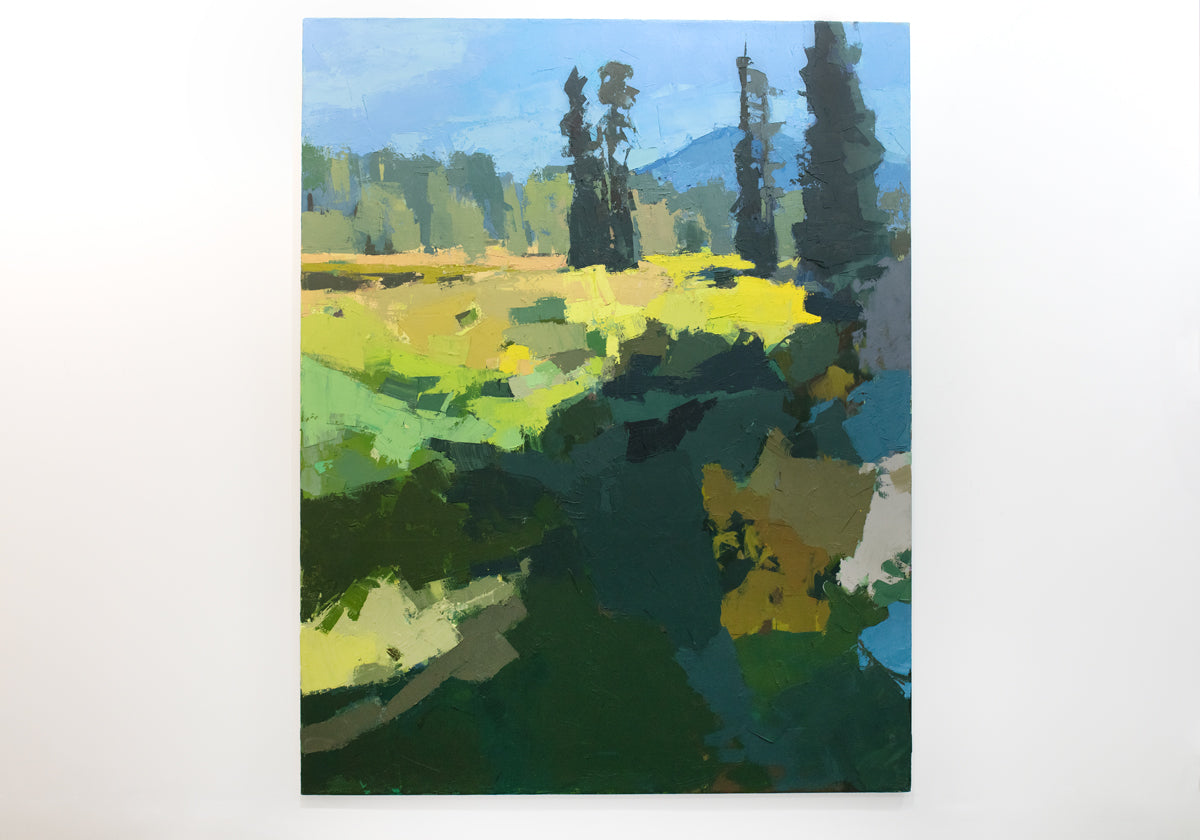 An abstracted blue and yellow landscape painting hangs on a white wall. 