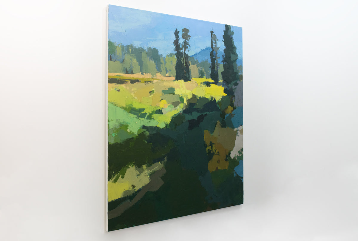 An abstracted blue and yellow landscape painting hangs on a white wall.