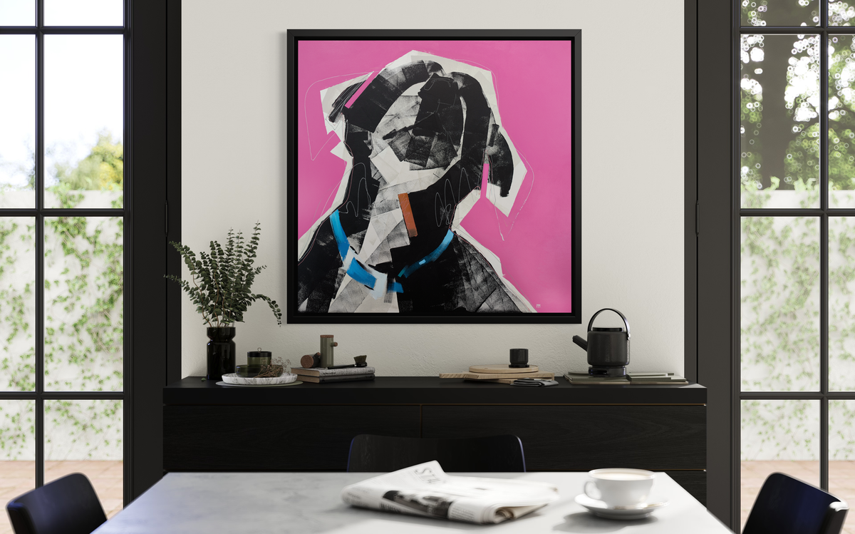 A pink, black, white and blue abstract dog print in a black floater frame hangs on a white wall above a black buffet with various decorative accessories.