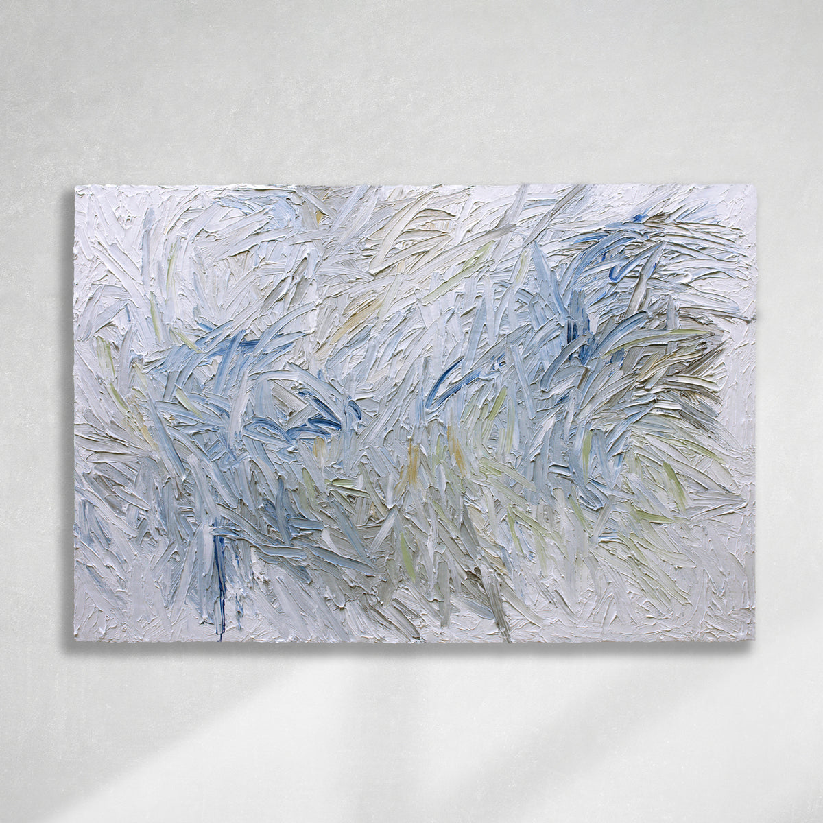 Original abstract painting by Teo Guererra with very textured blue and white brushstrokes hanging on a white sunlit wall.