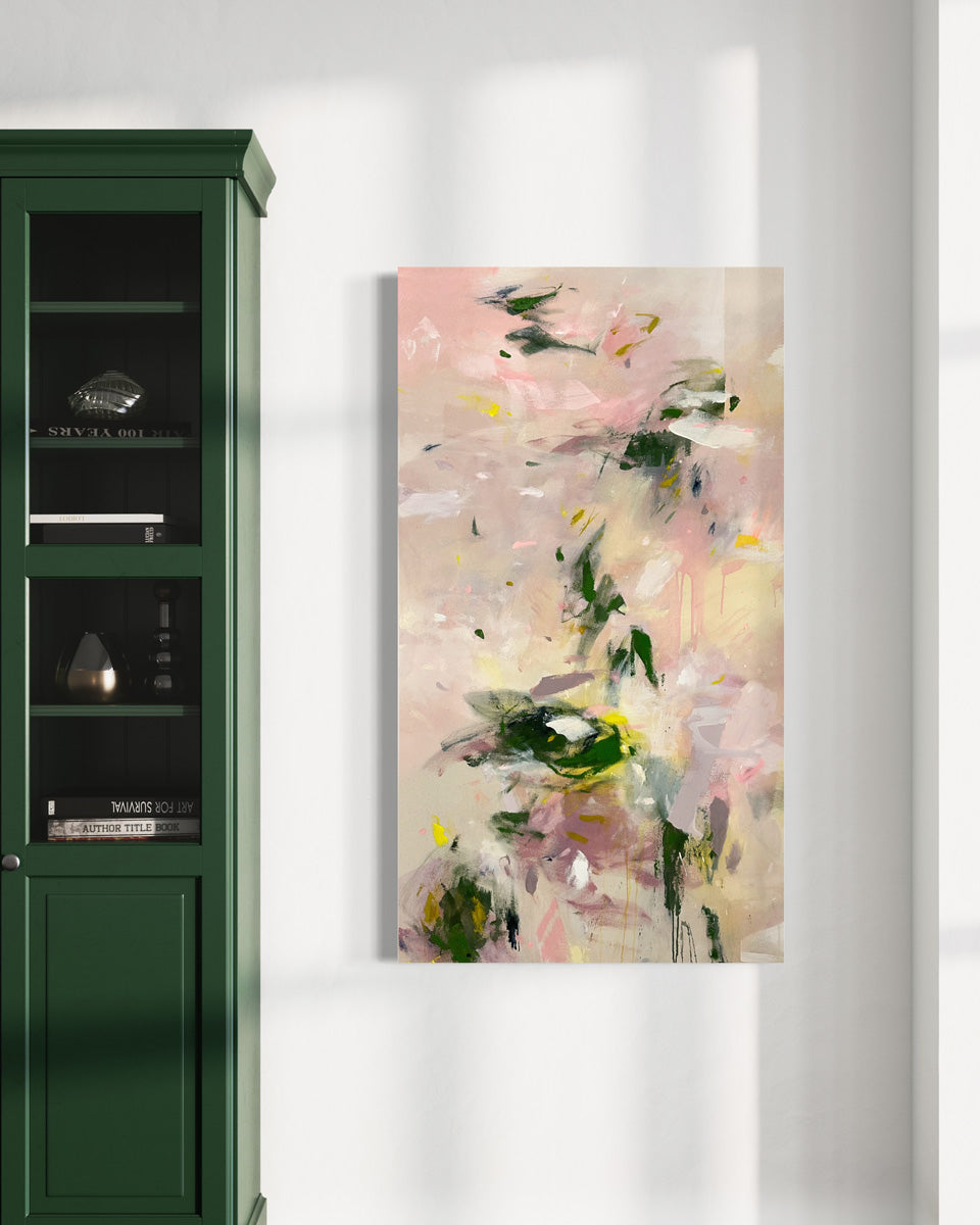 A pink and green abstract painting hangs on a white wall to the right of a green cabinet with glass windows. 