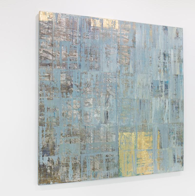 A blue and gold abstract painting hangs on a white wall.
