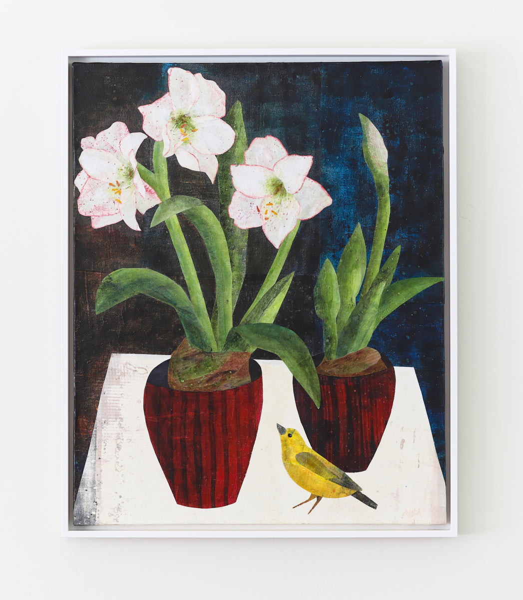 A framed still life painting featuring two potted white flowers with green stems and leaves, a small yellow bird, and a dark blue background, displayed on a light wall.