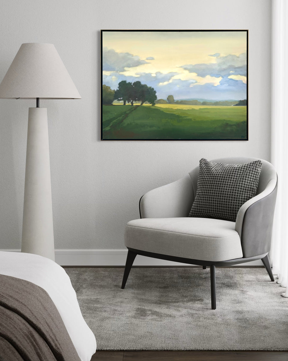 Modern living room with a gray armchair, lamp, and landscape painting on the wall.