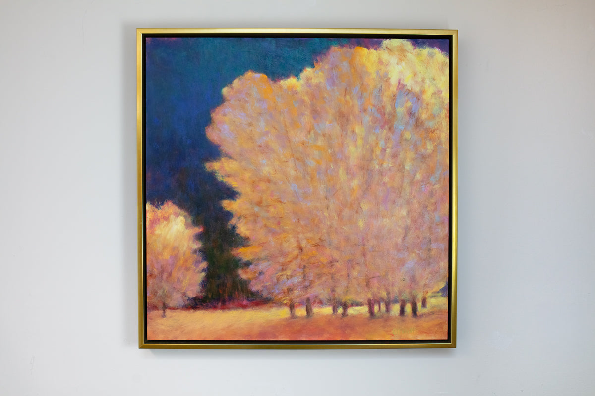 Framed painting of trees with a gold frame on a white wall