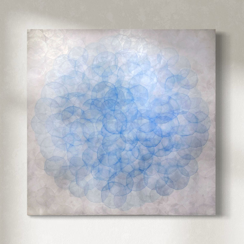 An abstract painting featuring a circular pattern with blue metallic accents on a cradled birch panel.