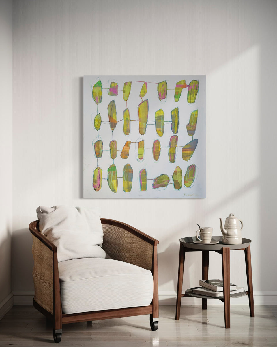 Abstract art piece on a wall above a chair in a room.
