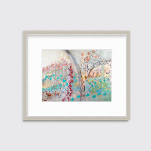 A multicolored abstract floral print in a silver frame with a mat hangs on a white wall.