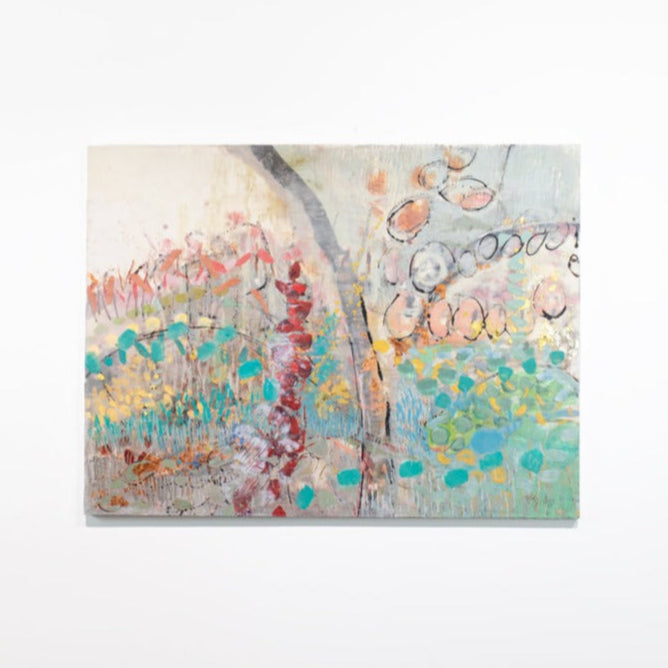 An abstract multicolored painting hangs on a white wall. 