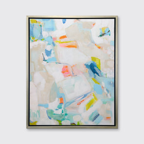 A white, beige, blue and pink abstract print in a silver floater frame hangs on a white wall.