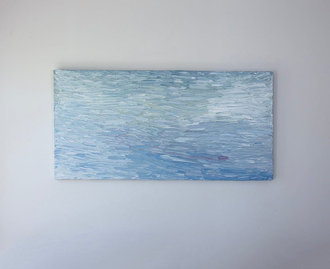 A abstract painting with blue textured brushstrokes is hung on a gallery wall.