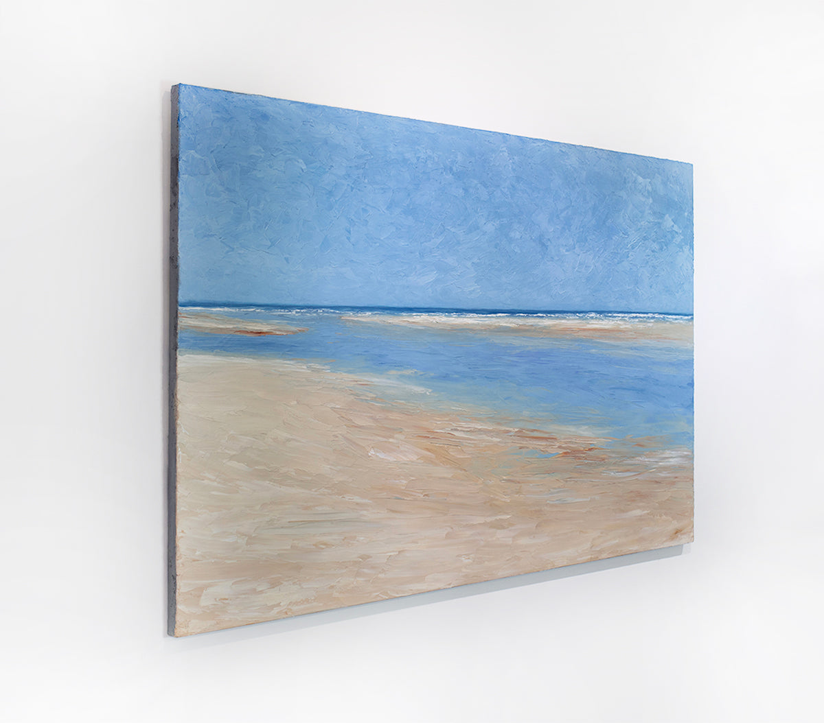 A textured blue and beige coastal painting of a beach hangs on a white wall.