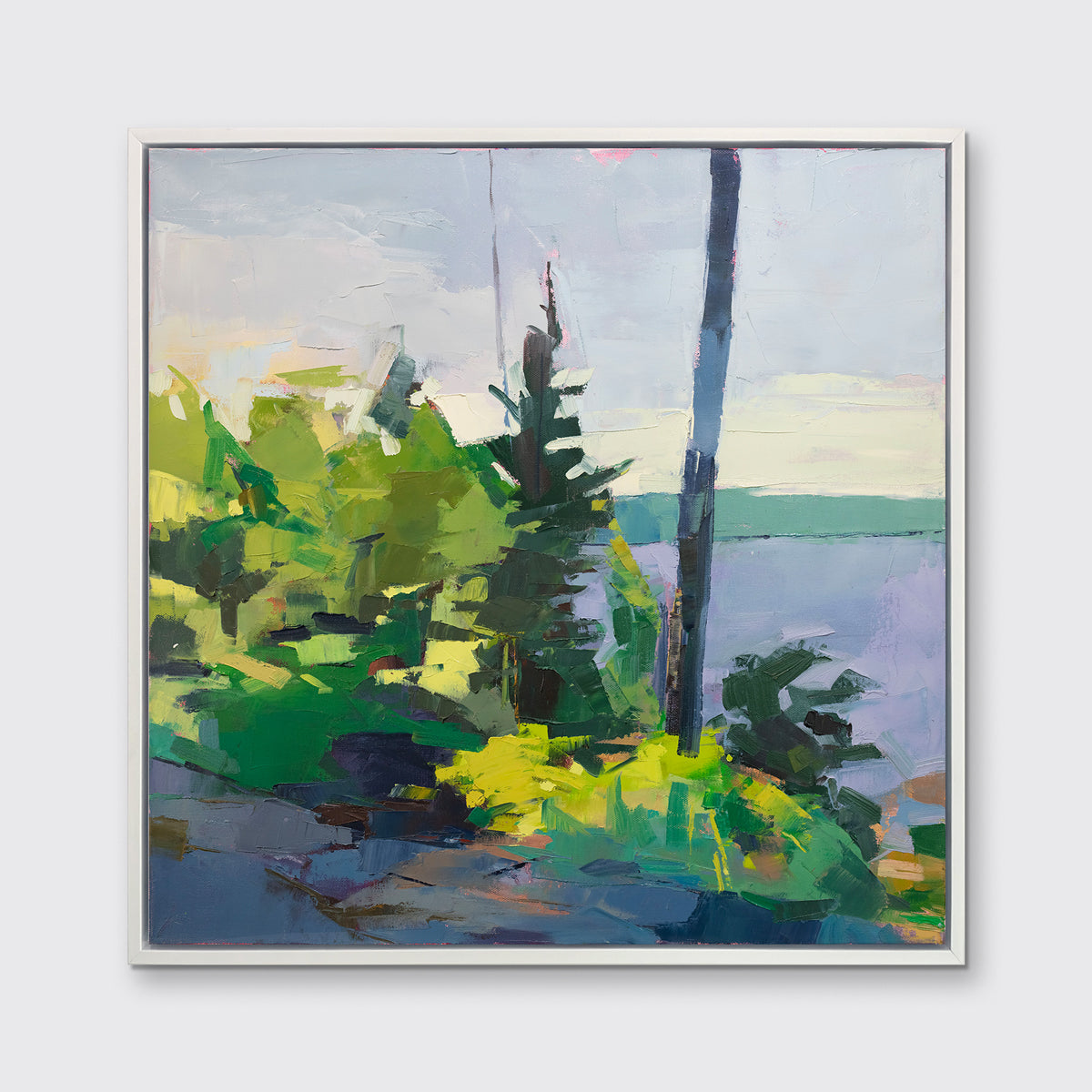 An abstract blue and green landscape print framed in a white frame hangs on a white wall.