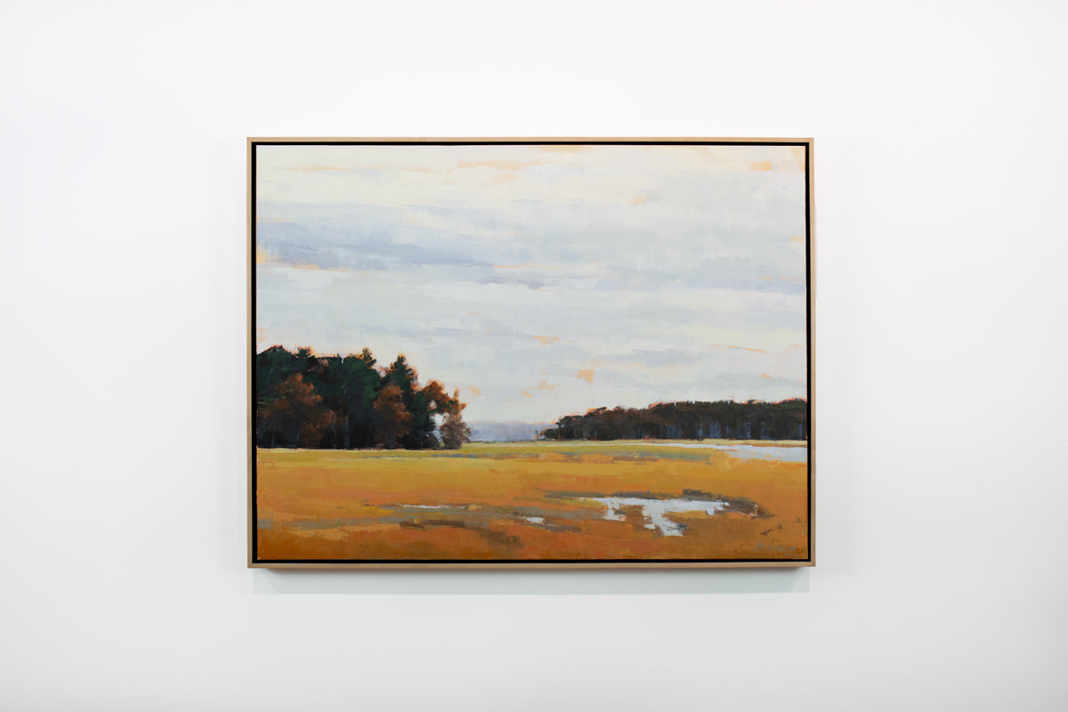 A light blue, dark green and shades of orange abstract landscape painting by Molly Doe Wensberg hangs in a light wood floater frame on a white wall.