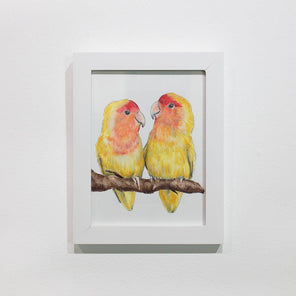 A framed illustration of yellow and orange birds sitting on a branch hangs on a white wall. 